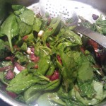 Tossing the baby spinach leaves into the warm bacon vinaigrette