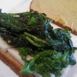 Mustard coating on one side of the bread, cheese and broccoli rabe on the other