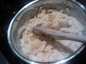 Grated Swiss cheese being added to the béchamel sauce