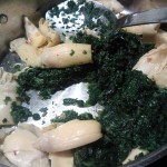 Sautéing the spinach and quartered artichoke hearts with garlic and olive oil