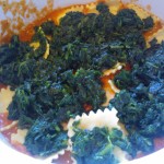 The first layer of marinara sauce, ravioli & spinach