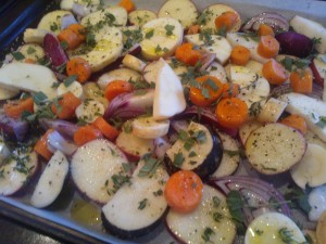A mixture of root vegetables sprinkled with herbs, ready to be roasted
