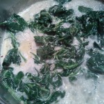 Sautéed spinach cooking with heavy cream and Parmesan cheese