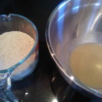 The dry ingredients beside the bowl of yeast, sugar & water