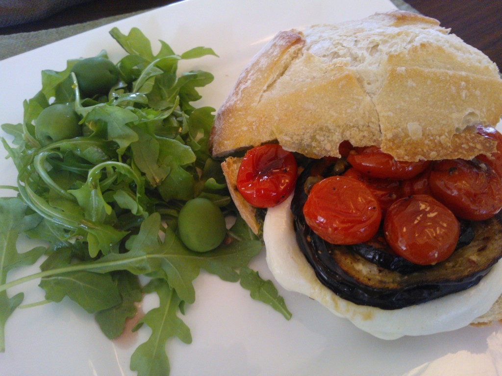 The sandwich served with a simple arugula salad and olives