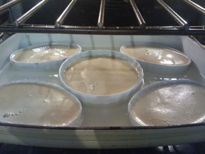 The individual creme brulees cooking in a water bath in the oven